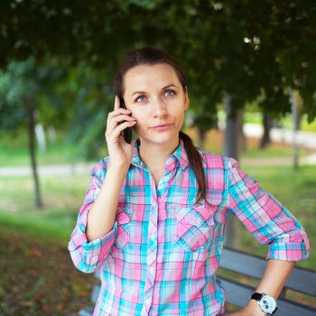 Portrait of a young woman in a park talking on the phone