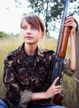 Young beautiful girl with a shotgun in an outdoor