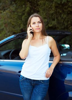 Caucasian girl on a cell phone service or tow truck traffic near the cabriolet car