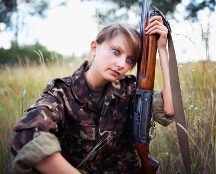 Young beautiful girl with a shotgun in an outdoor