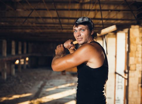 Muscular man with baseball bat on the ruins