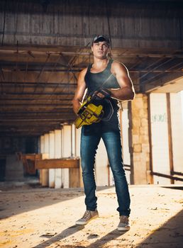 Muscular man with a chainsaw on the ruins