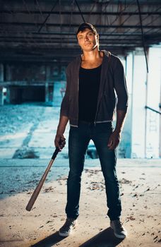 Muscular man with baseball bat on the ruins