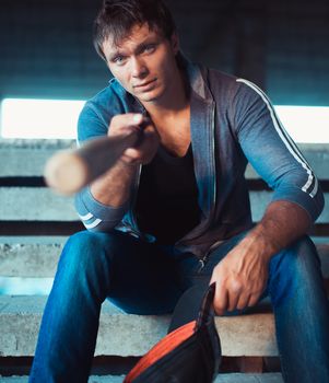 Muscular man with baseball bat on the ruins