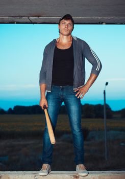 Muscular man with baseball bat on the ruins