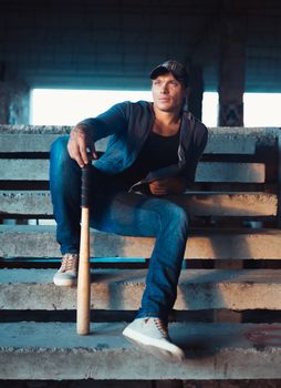 Muscular man with baseball bat on the ruins