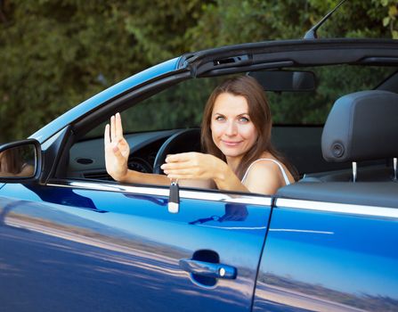 Smiling caucasian woman showing key in a cabriolet car