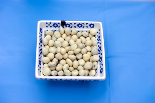 A bowl of pebbles on a table with blue cloth