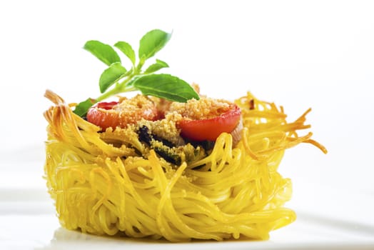 pasta nest arranged on a white porcelain plate with tomatoes parmesan and some leaves of basil