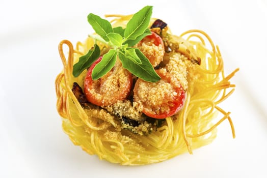 pasta nest arranged on a white porcelain plate with tomatoes parmesan and some leaves of basil