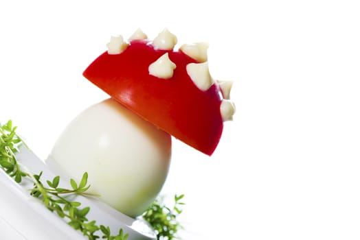 Funny food - boiled egg, cover with a tomato with mayonnaise points on leek bed