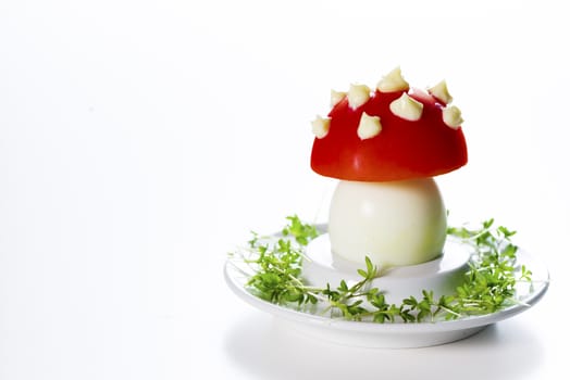 Funny food - boiled egg, cover with a tomato with mayonnaise points on leek bed