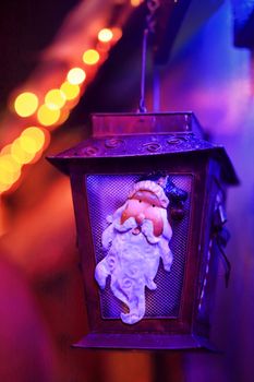 QUAKERS HILL, AUSTRALIA - DECEMBER 24 2014;  Closeup of tin lantern with Santa seasonal image decoration on house amidst glow of festive coloured twinkling led lights at Christmas time