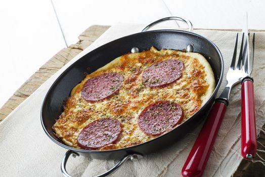 small samali pizza in a small black man with fork and knife