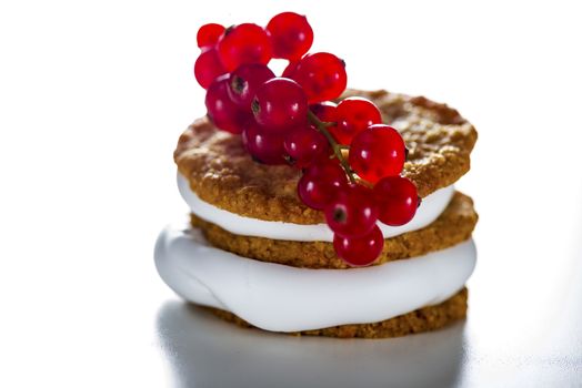 small cake with cream topping with currant on white background