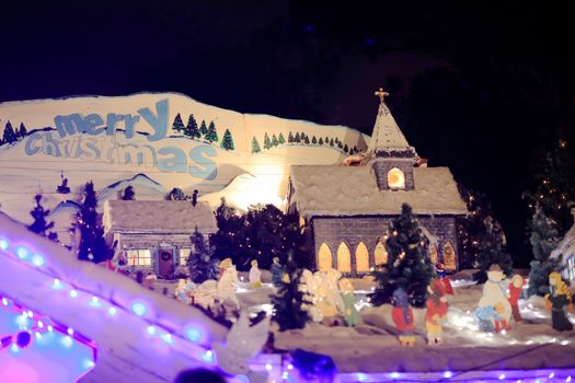 QUAKERS HILL, AUSTRALIA - DECEMBER 24 2014; The word Merry Christmas  with rooftop Christmas winter holiday scene including church building and village made from arts and crafts materials.  Background word and buildings in focus only