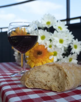Wine and Bread on a table with some flowers