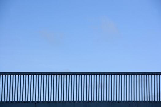 Railing of bridge towards blue sky