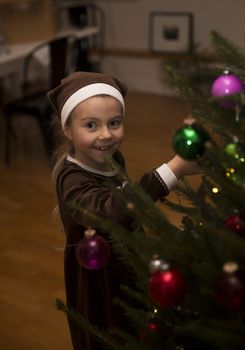 Happy Little Girl Hanging Decoration in a Christmas Tree