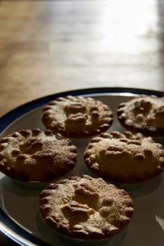Plate of mince pies shot against the light on a wooden table