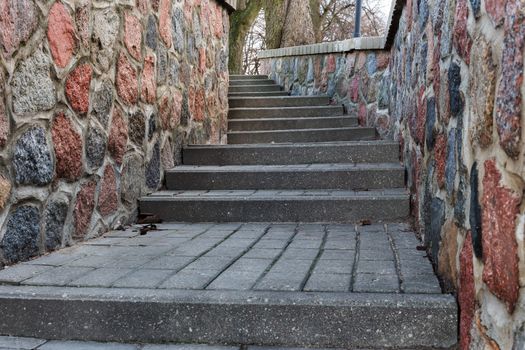 tortuous ascent of stone steps between the stone walls in autumn day