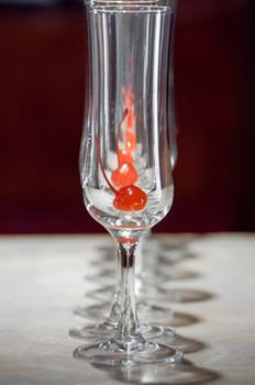 several sparkling wine glasses all in a line, one behind the other, each with a cherrie inside.