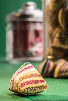 caramalised candy on a green background with two glass bottles filled with candy standing behind.