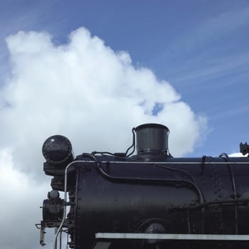 Old black steam locomotive against blue sky
