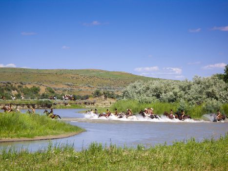 Crow Agency, Montana USA - June 27, 2009: Reenactment of the Battle of the Little Bighorn known as Custer's Last Stand. Young Indian warriors on horseback gallop across the river during battle reenactment.