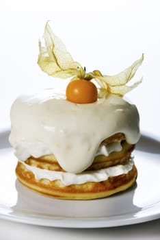 a stack of pancakes with cream and decorated with physalis on white background