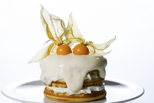 a stack of pancakes with cream and decorated with physalis on white background