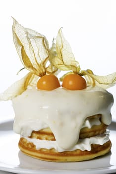 a stack of pancakes with cream and decorated with physalis on white background