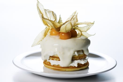 a stack of pancakes with cream and decorated with physalis on white background