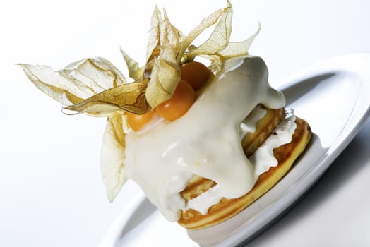 a stack of pancakes with cream and decorated with physalis on white background