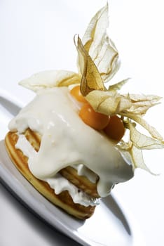 a stack of pancakes with cream and decorated with physalis on white background