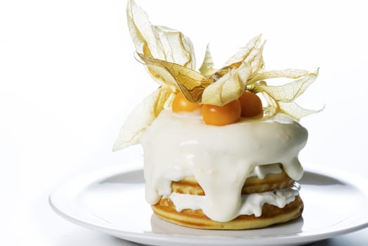 a stack of pancakes with cream and decorated with physalis on white background