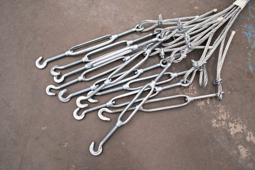 Turnbuckles and wire on the concrete floor of an industrial workshop.