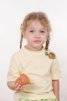 Three year old girl with pigtails and funny enthusiastically eating a bun