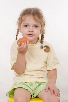 Three year old girl with pigtails and funny enthusiastically eating a bun