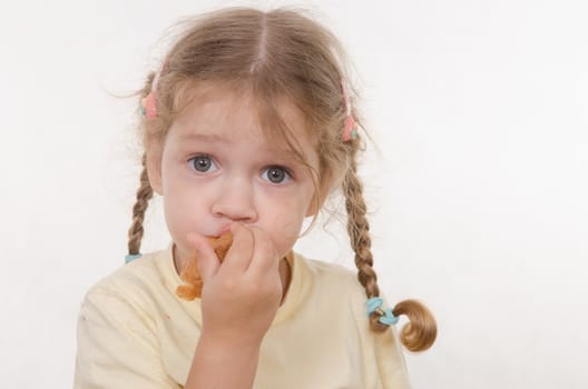 Three year old girl with pigtails and funny enthusiastically eating a bun