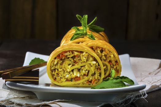 asian curry rice roll cutted as a sushi in a white plate on old wood table