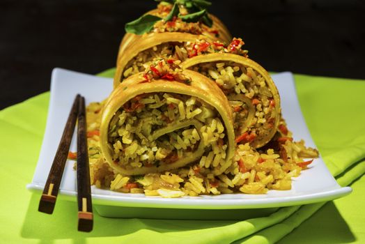 asian curry rice roll cutted as a sushi in a white plate on green napkin