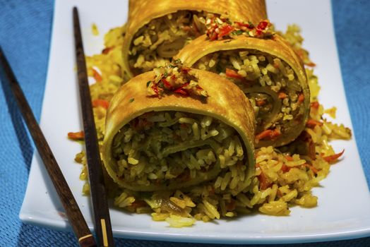 asian curry rice roll cutted as a sushi in a white plate on blue napkin