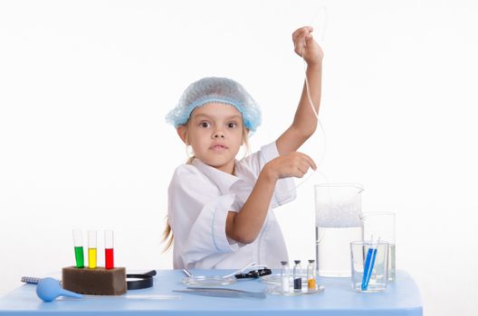 Chemist girl sitting at the table with the reagents in chemistry class and puts experiments