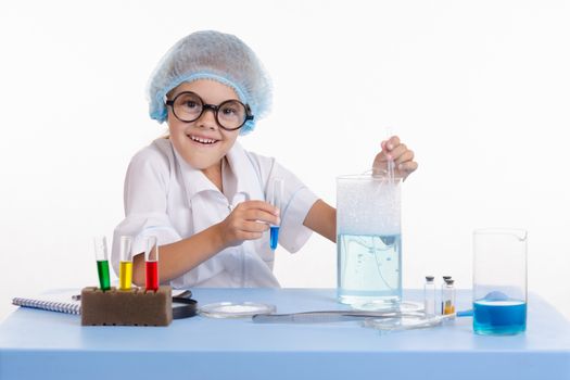 Chemist girl sitting at the table with the reagents in chemistry class and puts experiments