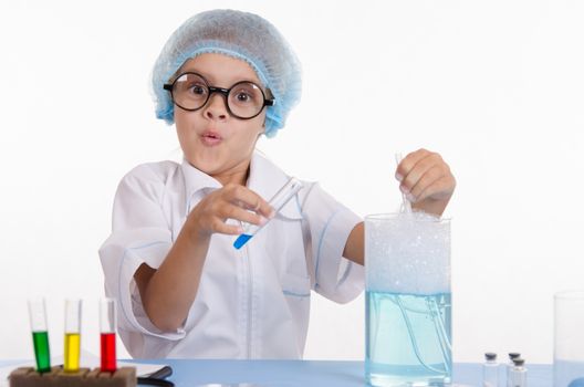 Chemist girl sitting at the table with the reagents in chemistry class and puts experiments