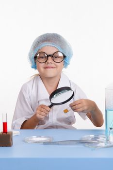 Chemist girl sitting at the table with the reagents in chemistry class and puts experiments