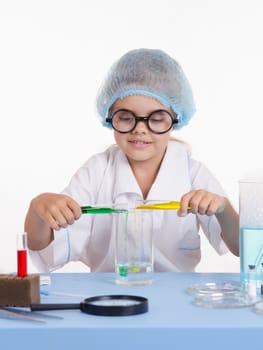 Chemist girl sitting at the table with the reagents in chemistry class and puts experiments