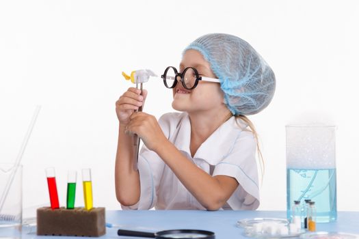 Chemist girl sitting at the table with the reagents in chemistry class and puts experiments