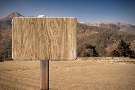 Blank wooden sign on field of farm. Concept of rural, idyllic, tranquility etc.